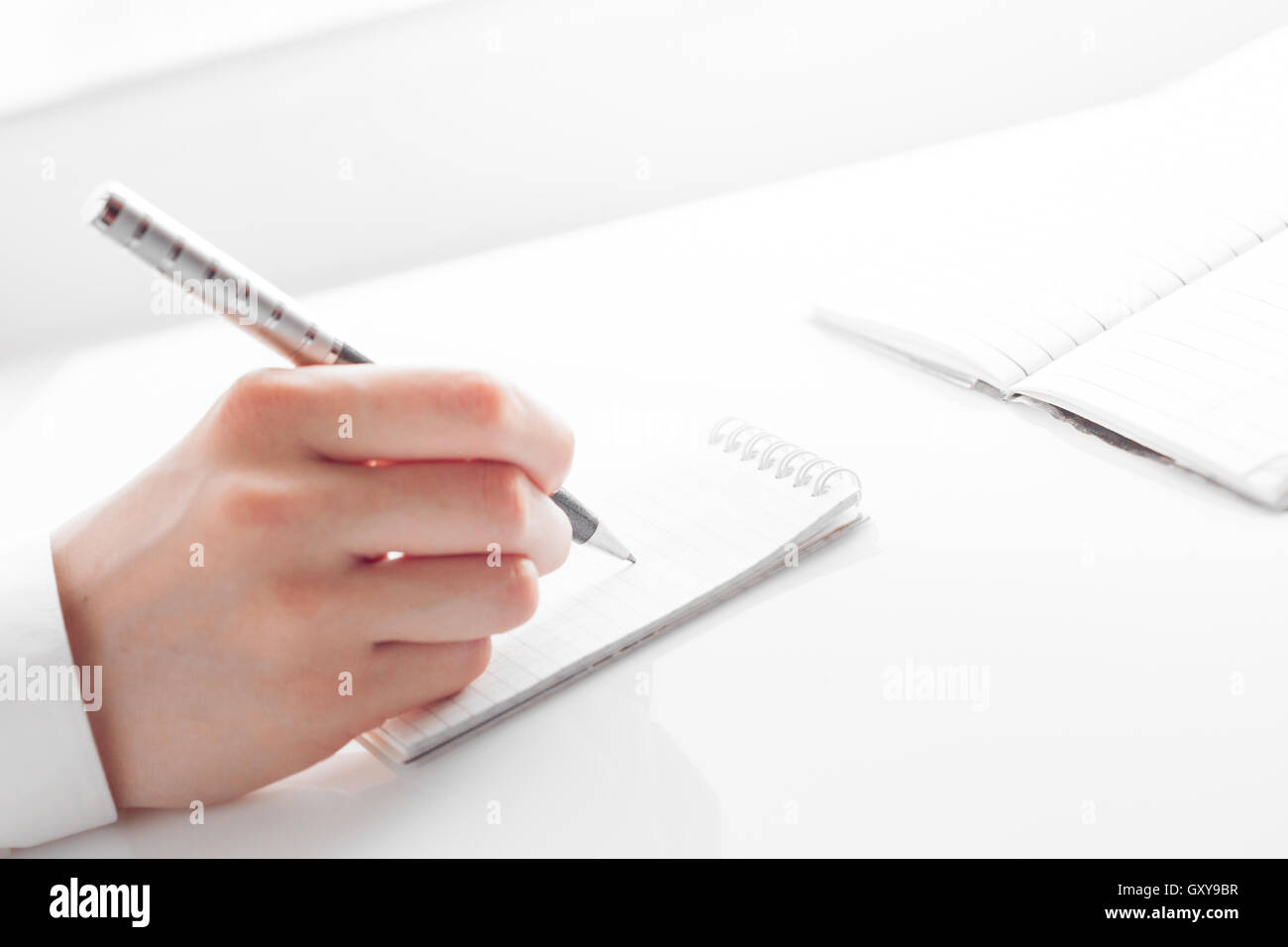 woman's hand writing entries in a notebook Stock Photo
