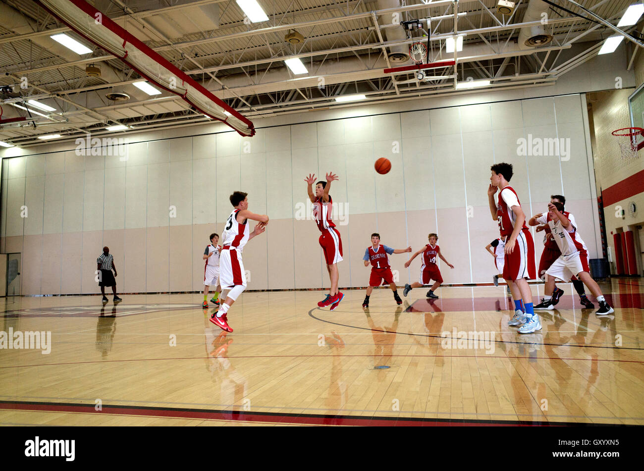 Defensive teen basketball player leaps in air in an unsuccessful attempt to block ball. White Bear Lake Minnesota MN USA Stock Photo