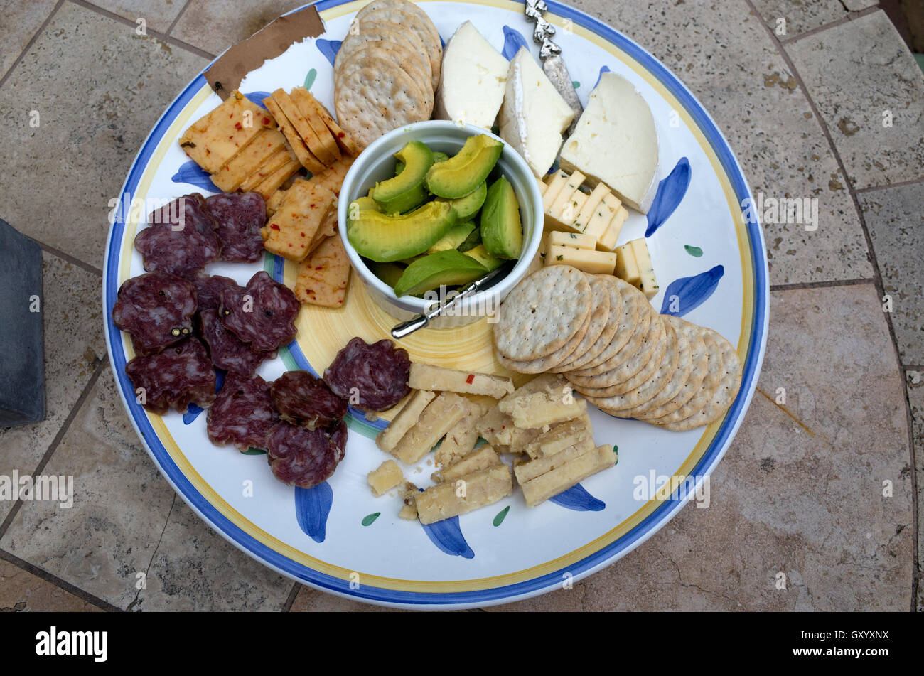 Array of cheese, crackers and avocado on a round appetizer platter at a