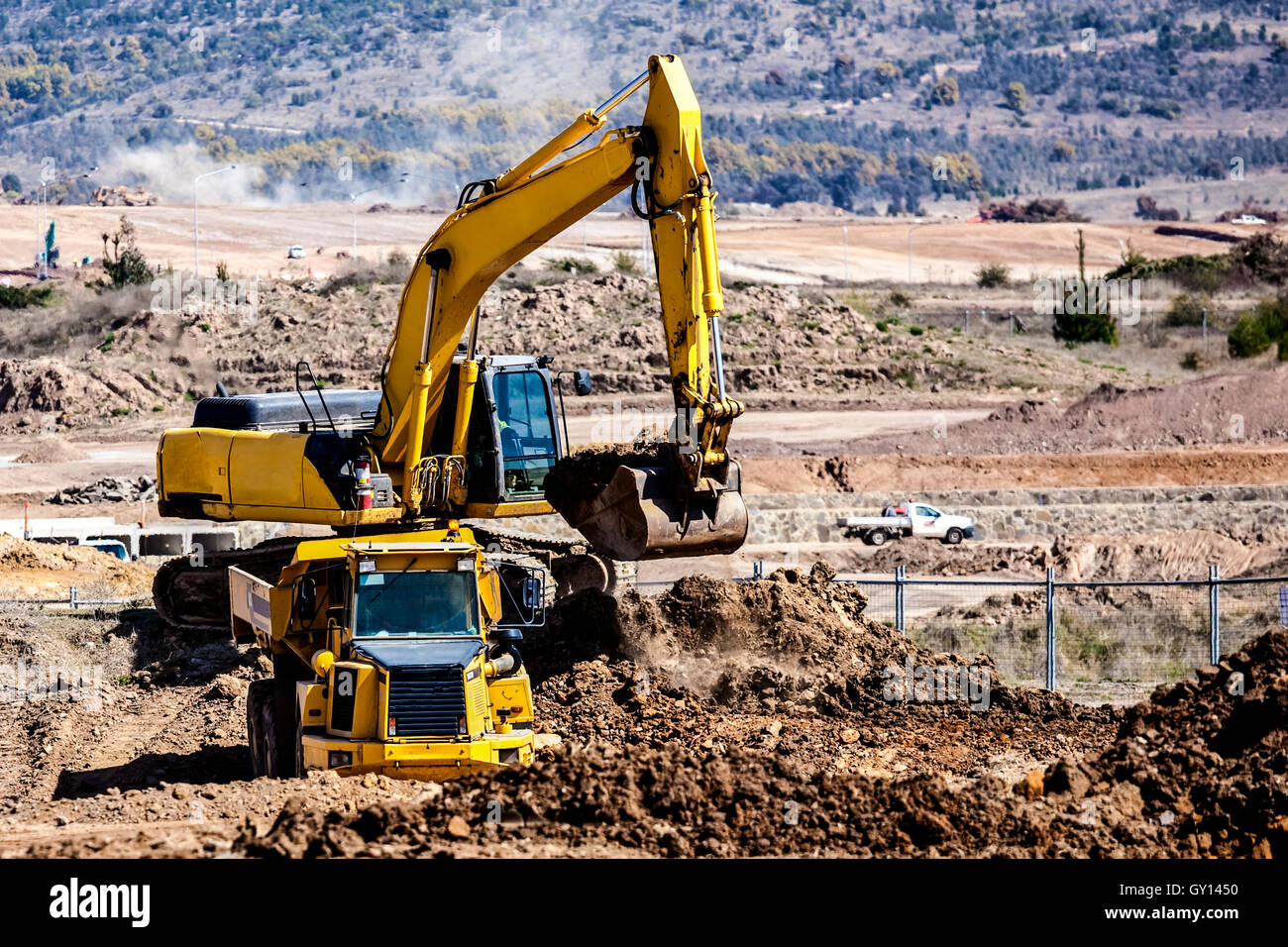 Earth moving machine loading soil into truck on construction site Stock Photo