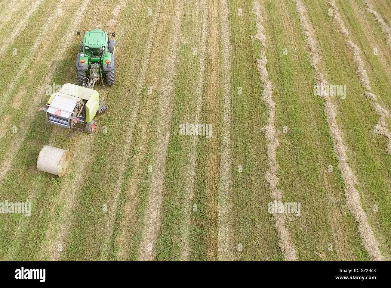 Aerial view of tractor with round baler rolling bales of straw on ...