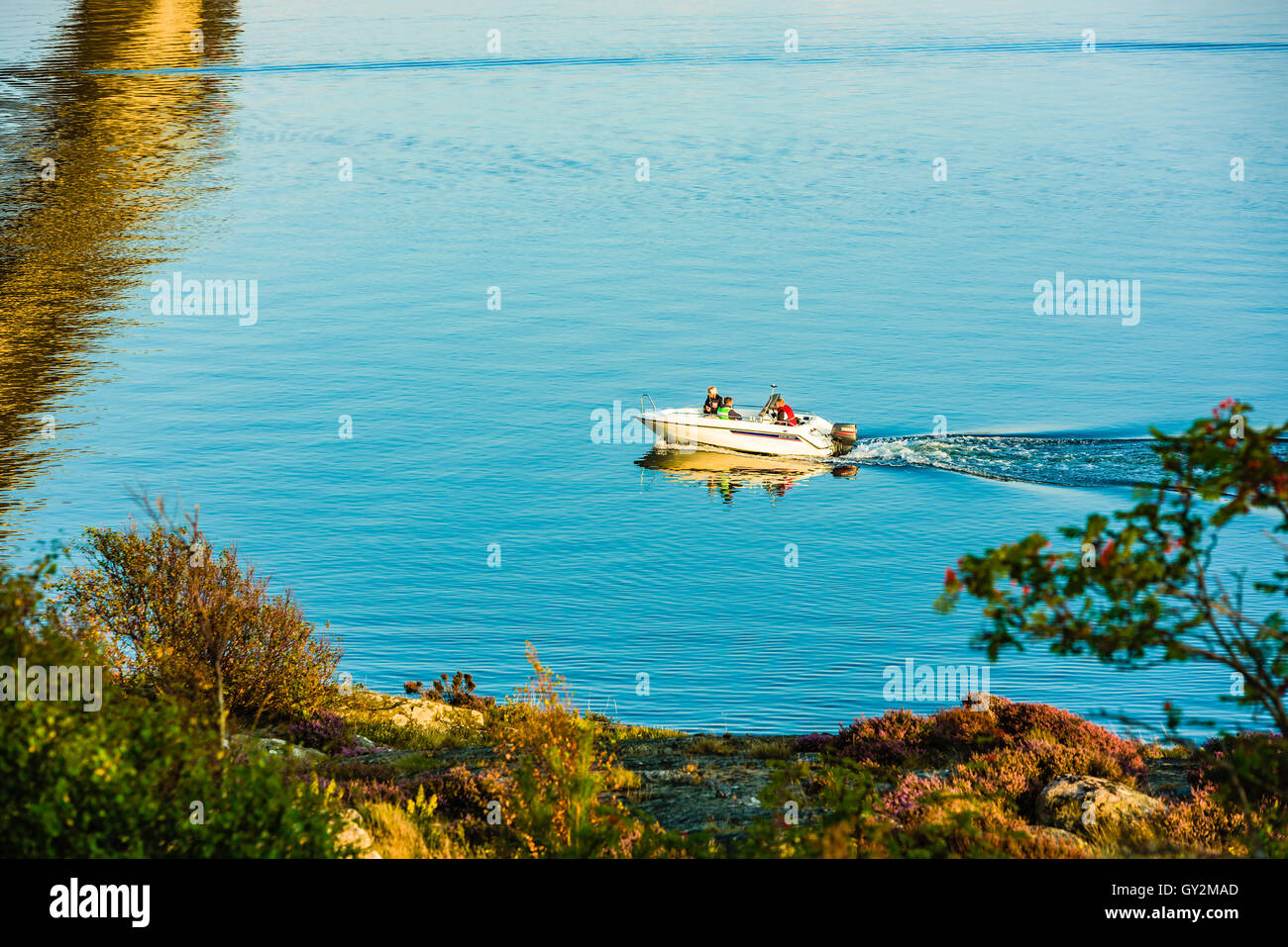 Marstrand, Sweden - September 8, 2016: Environmental documentary of three persons in a motorboat cruising close to land in motio Stock Photo