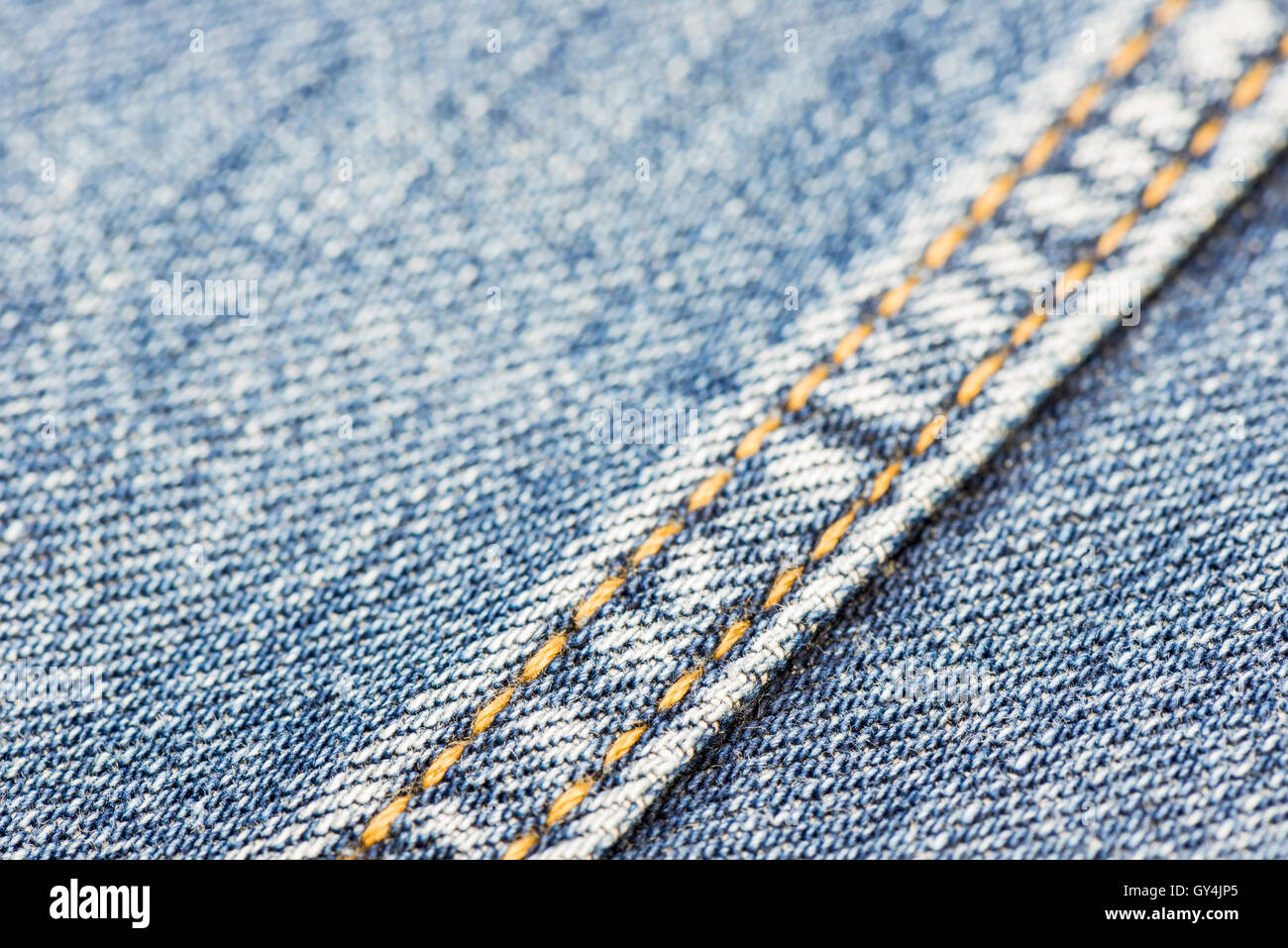 Blue denim with yellow stitching as background picture Stock Photo