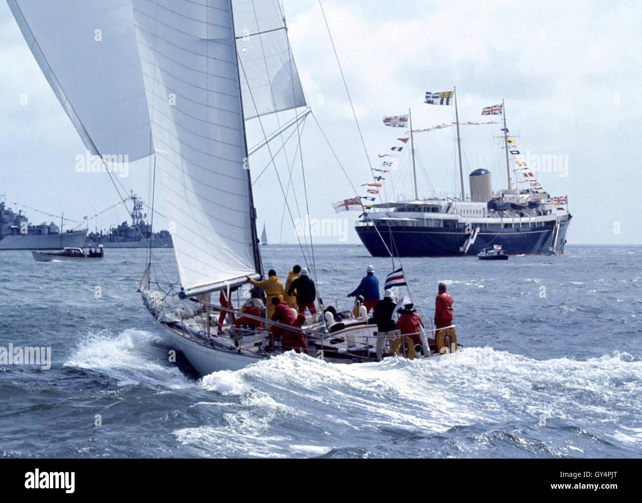 AJAX NEWS PHOTOS. 1971. SOLENT, ENGLAND. - ADMIRAL'S CUP - AMERICAN ENTRY YANKEE GIRL POWERS TOWARD COWES ROADS WITH THE ROYAL YACHT HMRY BRITANNIA AND NAVAL GUARDSHIPS IN BACKGROUND. PHOTO:JONATHAN EASTLAND/AJAX REF:C7105D6 3 Stock Photo