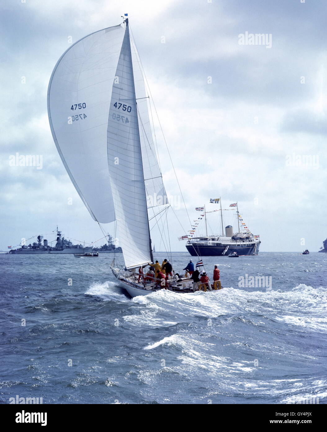 AJAX NEWS PHOTOS. 1971. SOLENT, ENGLAND. - ADMIRAL'S CUP - AMERICAN ENTRY YANKEE GIRL POWERS TOWARD COWES ROADS WITH THE ROYAL YACHT HMRY BRITANNIA AND NAVAL GUARDSHIPS IN BACKGROUND. PHOTO:JONATHAN EASTLAND/AJAX REF:C7105D6 Stock Photo