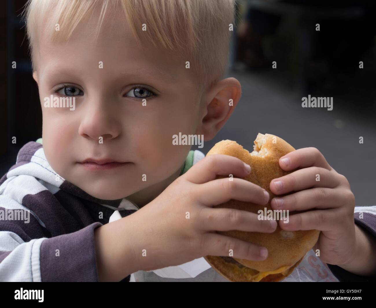 Little Caucasian boy eating burger Stock Photo Alamy