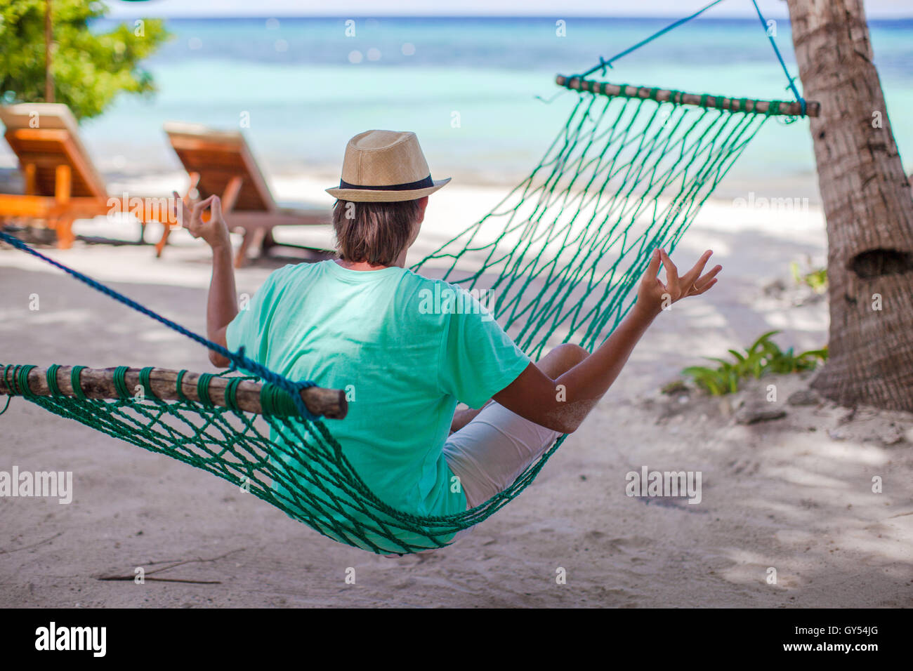 Hat Position Young man sitting in hat on the lotus position at hammock Stock Photo ...