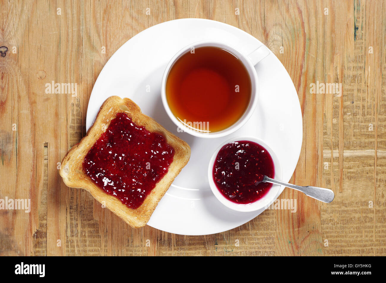 Cup of tea and toast with jam on old wooden table. Top view Stock Photo