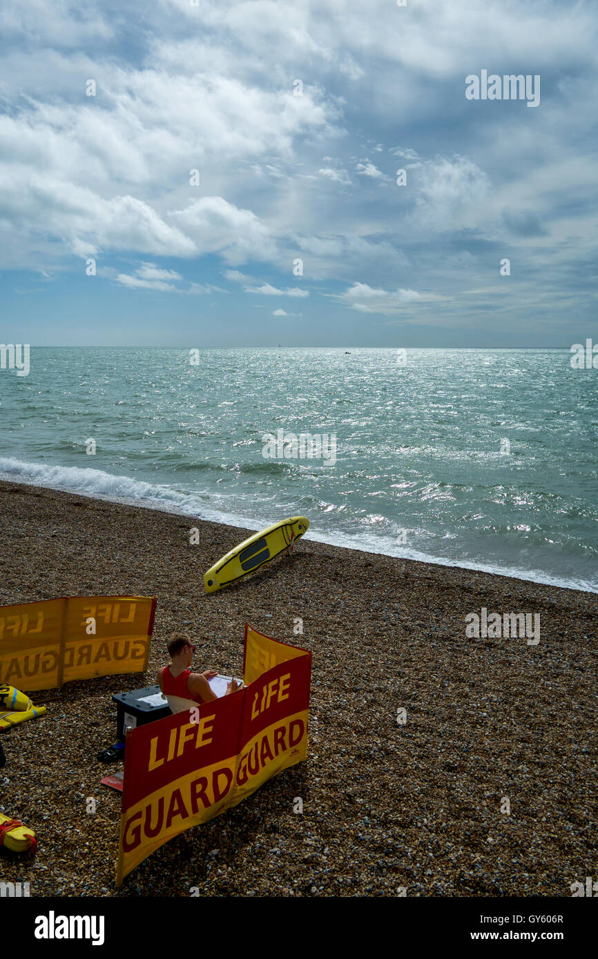 Life gaurd on duty on Brighton beach, Sussex, United Kingdon. Sitting on beach surrounded by life guard windbreak and surf rescu Stock Photo