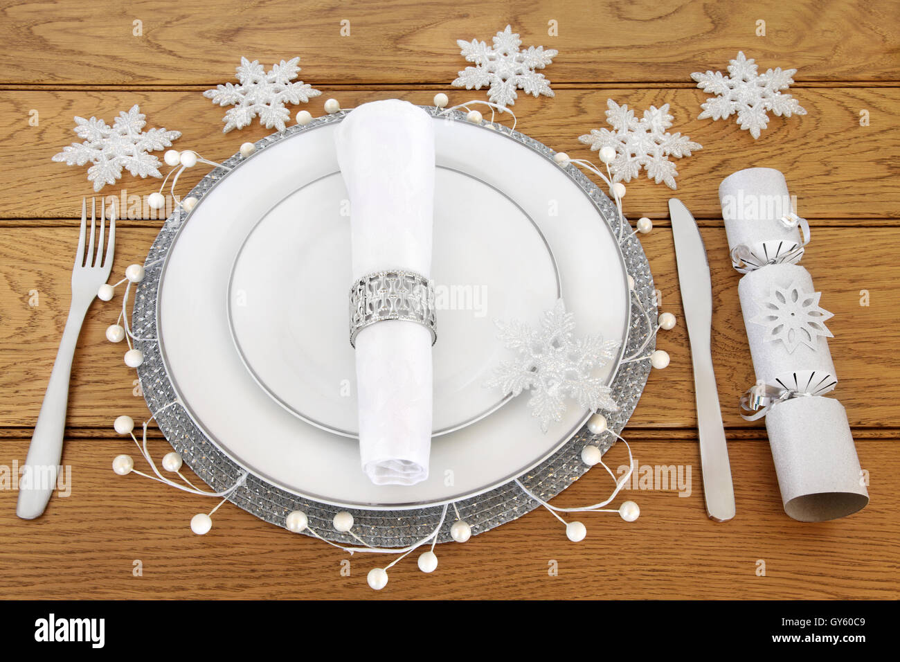 Christmas dinner table setting with white porcelain plates, cutlery,  serviette with silver napkin ring & snowflake baubles Stock Photo - Alamy