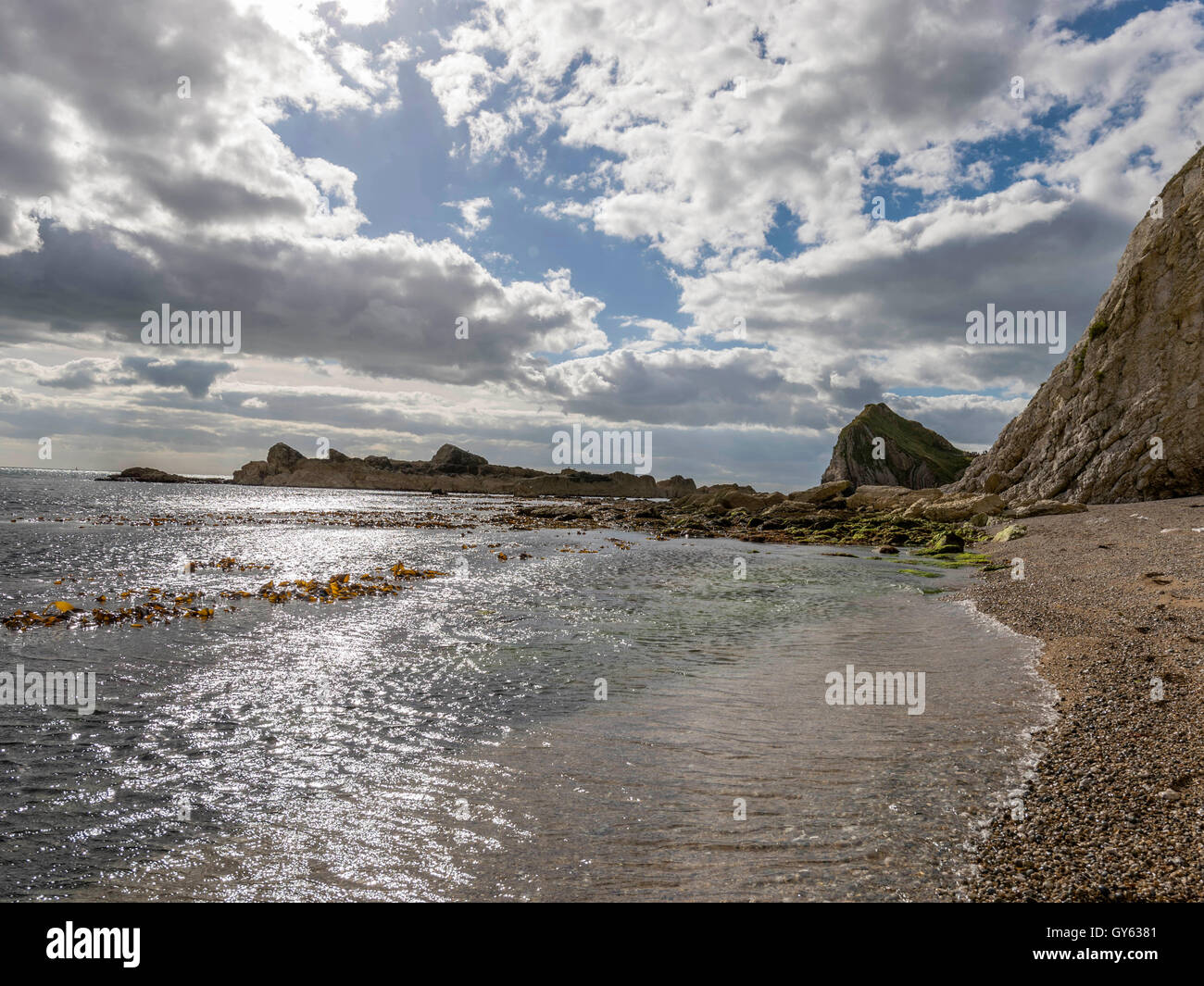 Landscape depicting the rocky Man O'War shoreline on fine summer day with Durdle Door headland in the background. Stock Photo