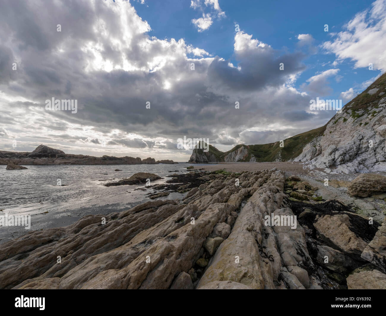 Landscape depicting the rocky shoreline of Man O'War beach on a fine summer day with Durdle Door headland in the background. Stock Photo