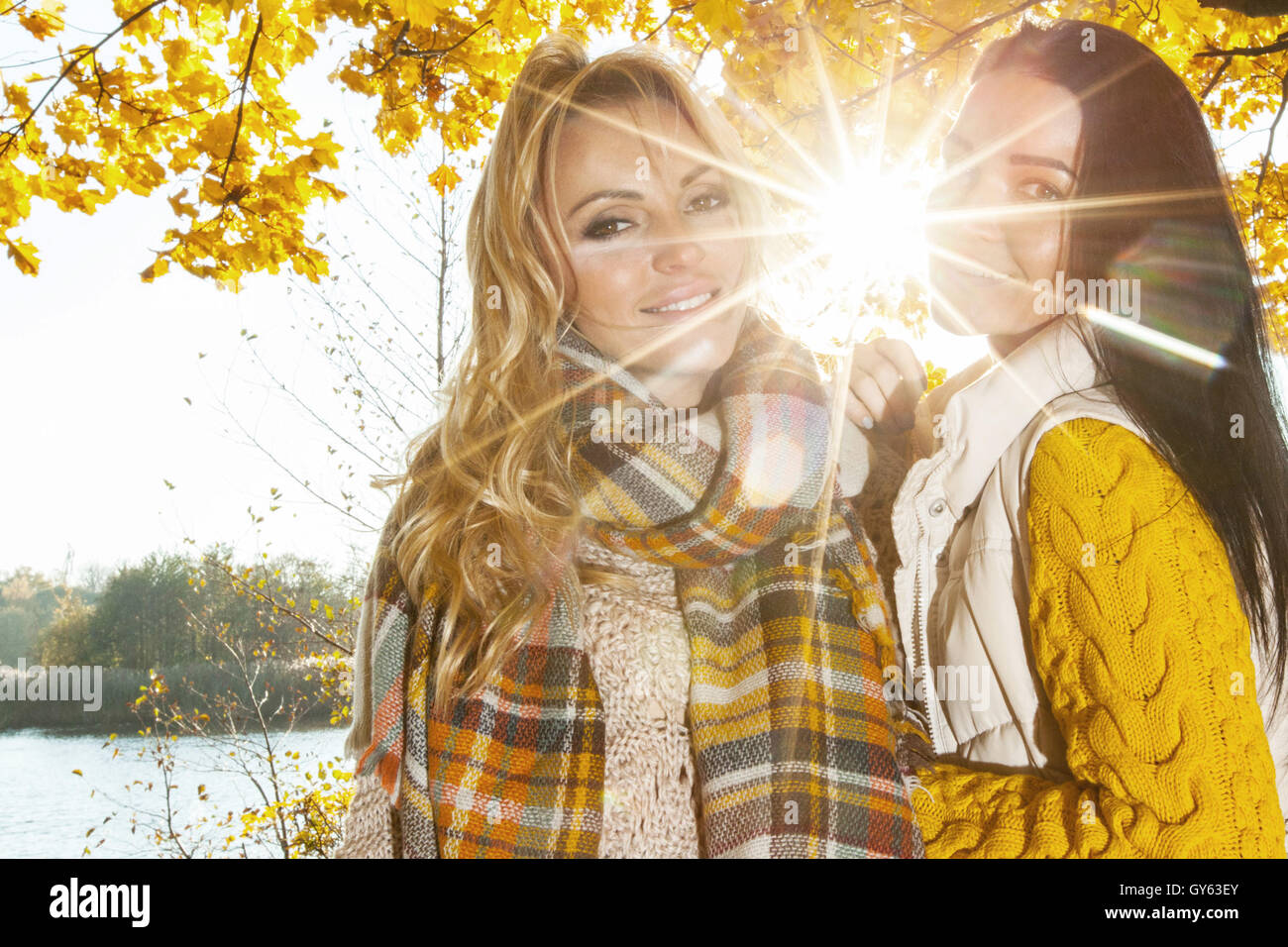 Two cheerful women in autumn park at sunny day Stock Photo - Alamy
