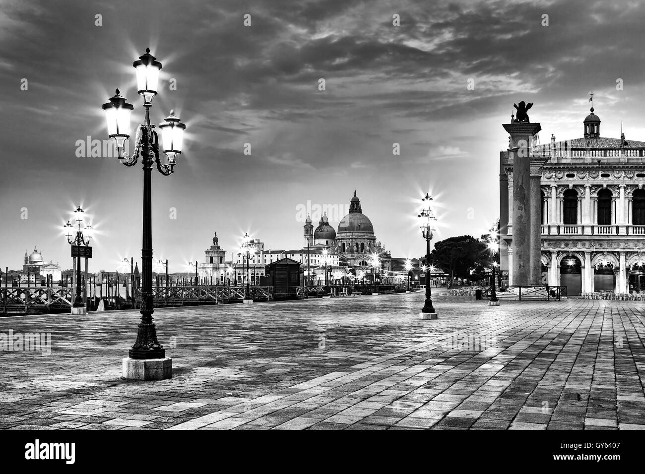 San Marco square piazza in Venice at sunrise with illuminated street lights in black-white image. Stock Photo