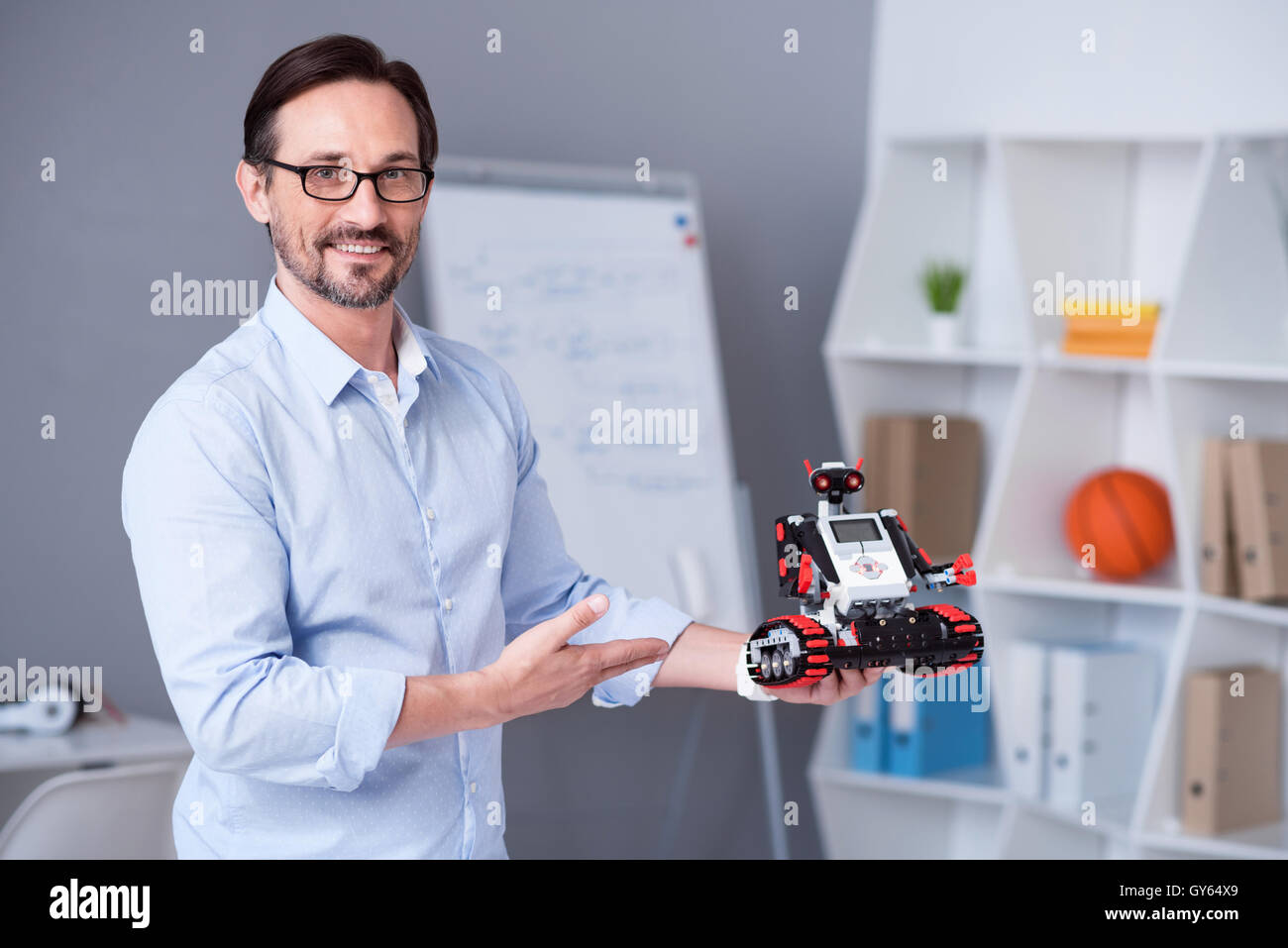 Smart male scientist in glasses presenting a little robot Stock Photo