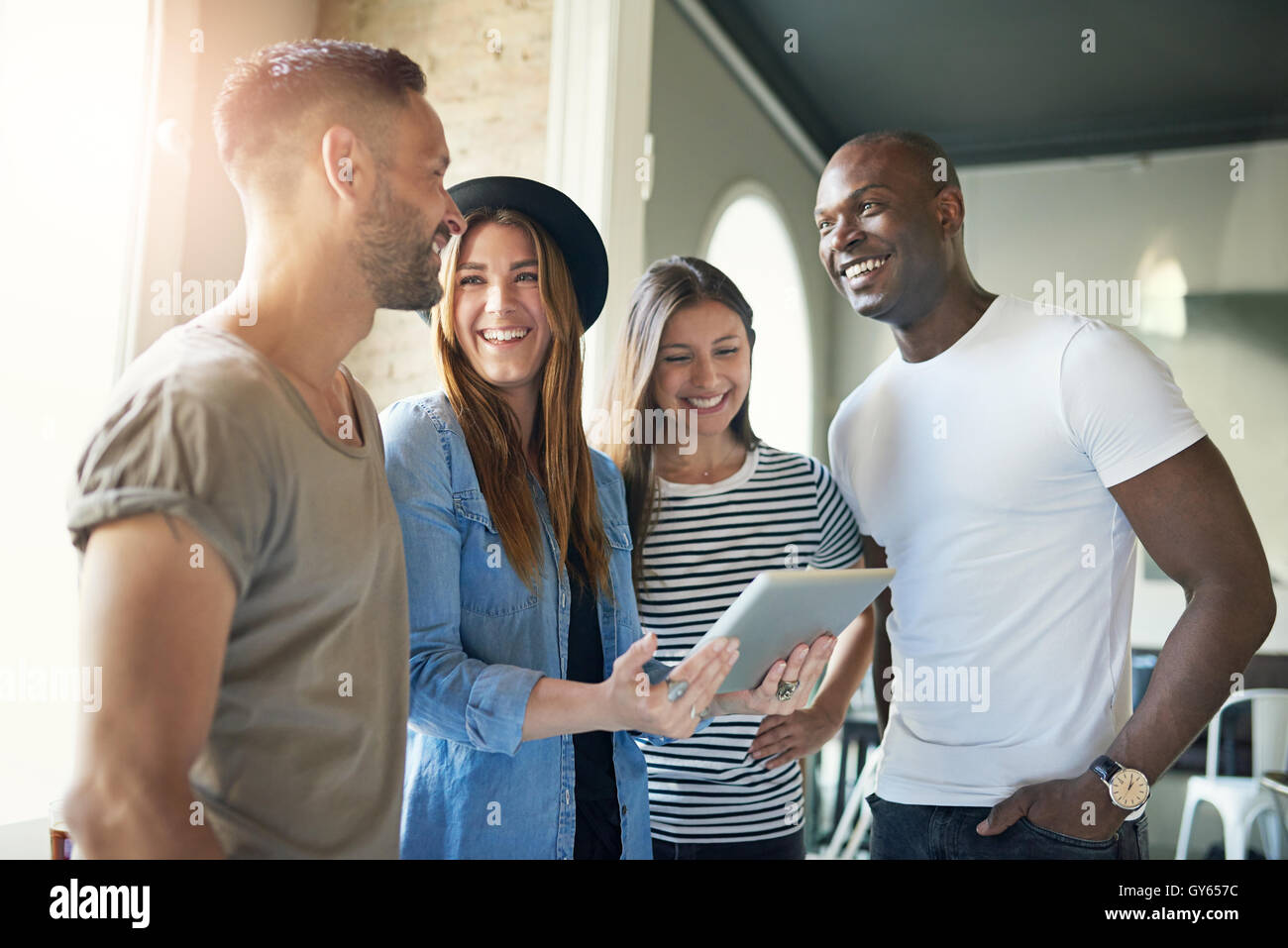 Successful young business team of enthusiastic modern young people in informal clothing standing in the office having a meeting Stock Photo