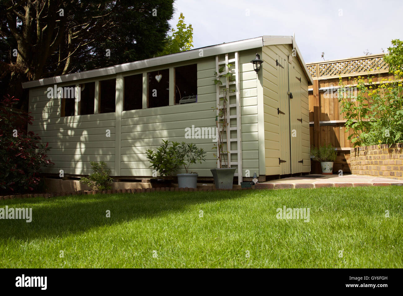 Garden shed painted sage pale green with lawn in front Stock Photo