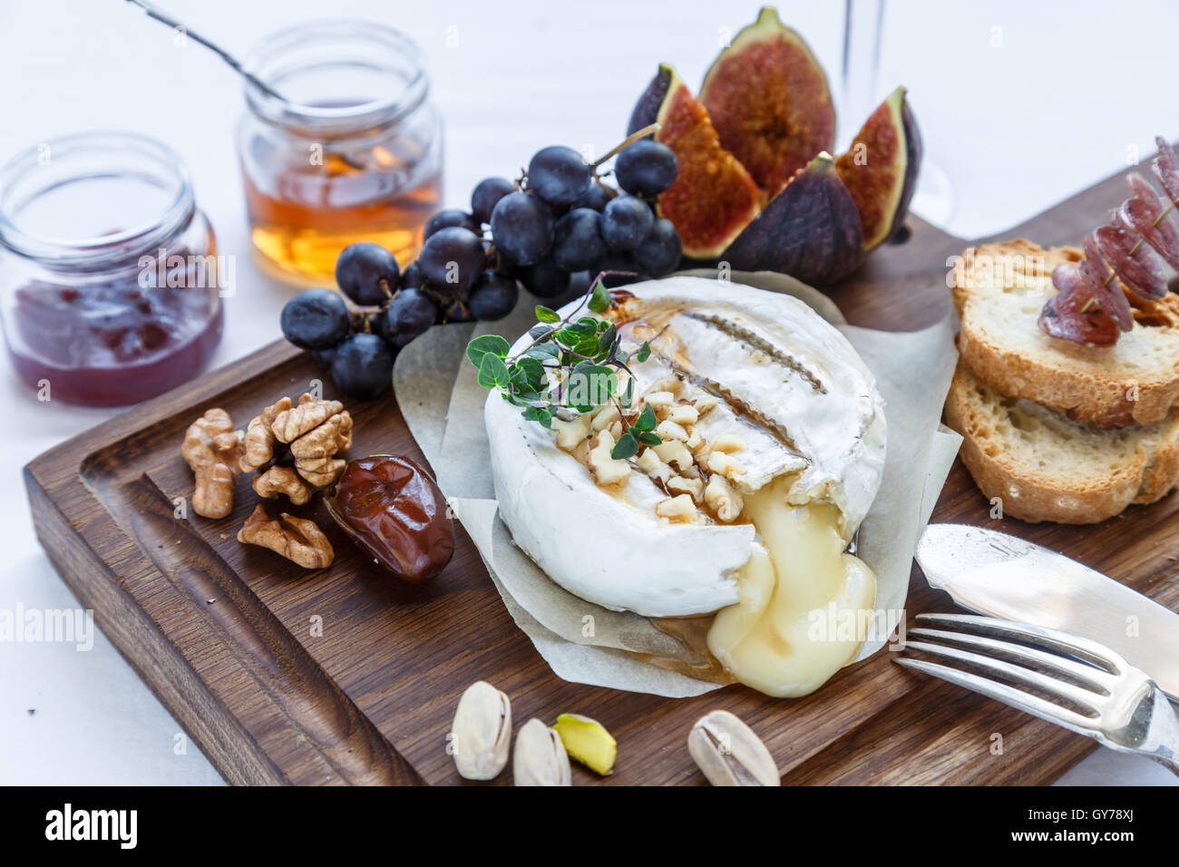 Baked camembert cheese with figs, honey, grapes and nuts. Top view Stock Photo