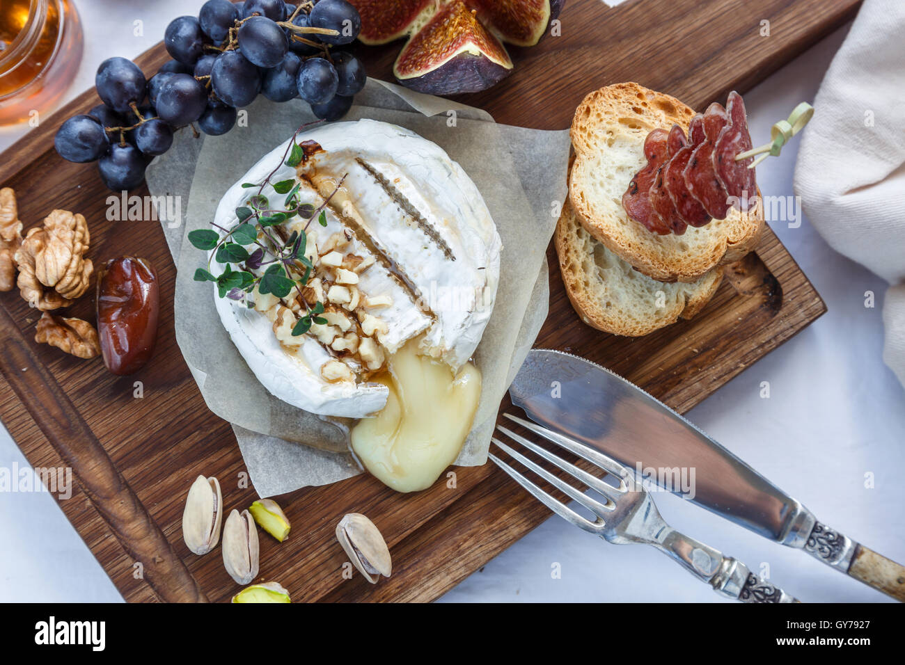 Baked camembert cheese with figs, honey, grapes and nuts. Top view