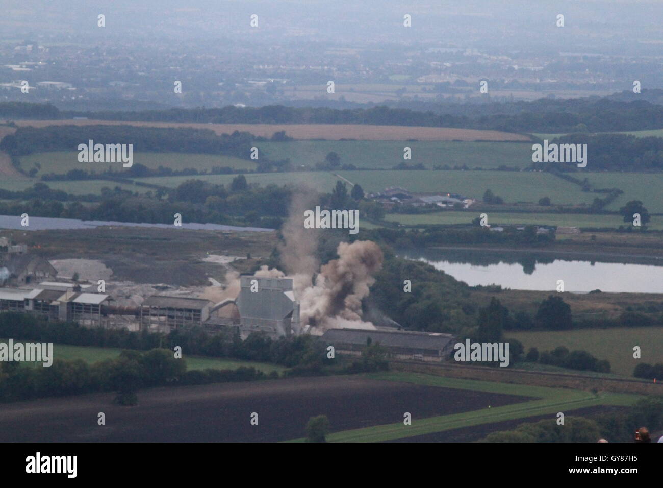 Westbury, UK, 18th Sept, 2016. The 122m high chimney of the westbury cement works, which has been a landmark of the wiltshire skyline since its construction during the 1960's is demolished using 216 charges after being mothballed in 2009.  The demolition comes after over 40 years of cement production at the site. The charges were detonated at 7am by 9 year old local schoolgirl Lilly Sargent after winning a drawing competition hosted by site owner Tarmac. Daniel Crawford / Alamy Live News Stock Photo