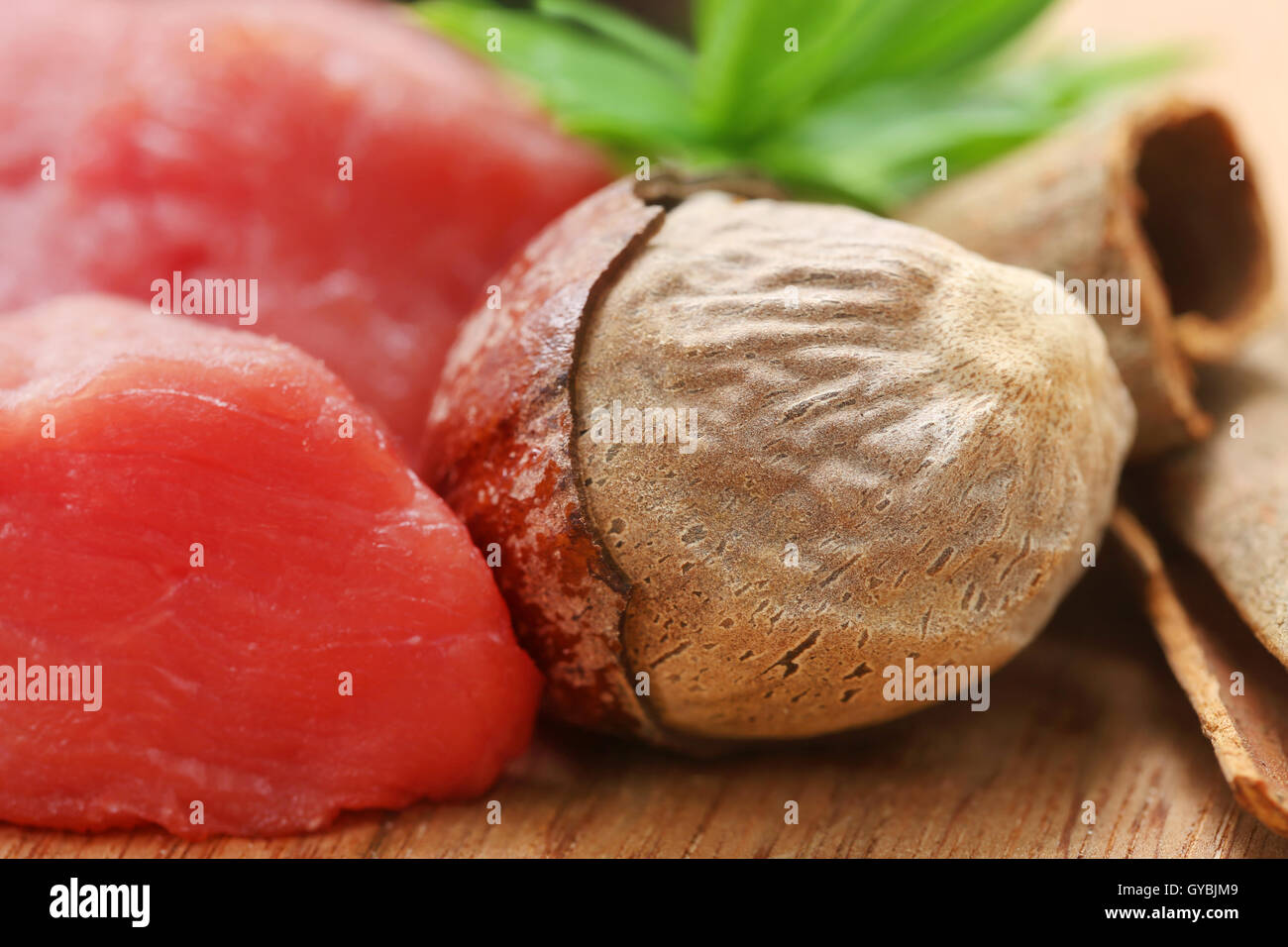Raw beef with nutmeg other spices on wooden surface Stock Photo