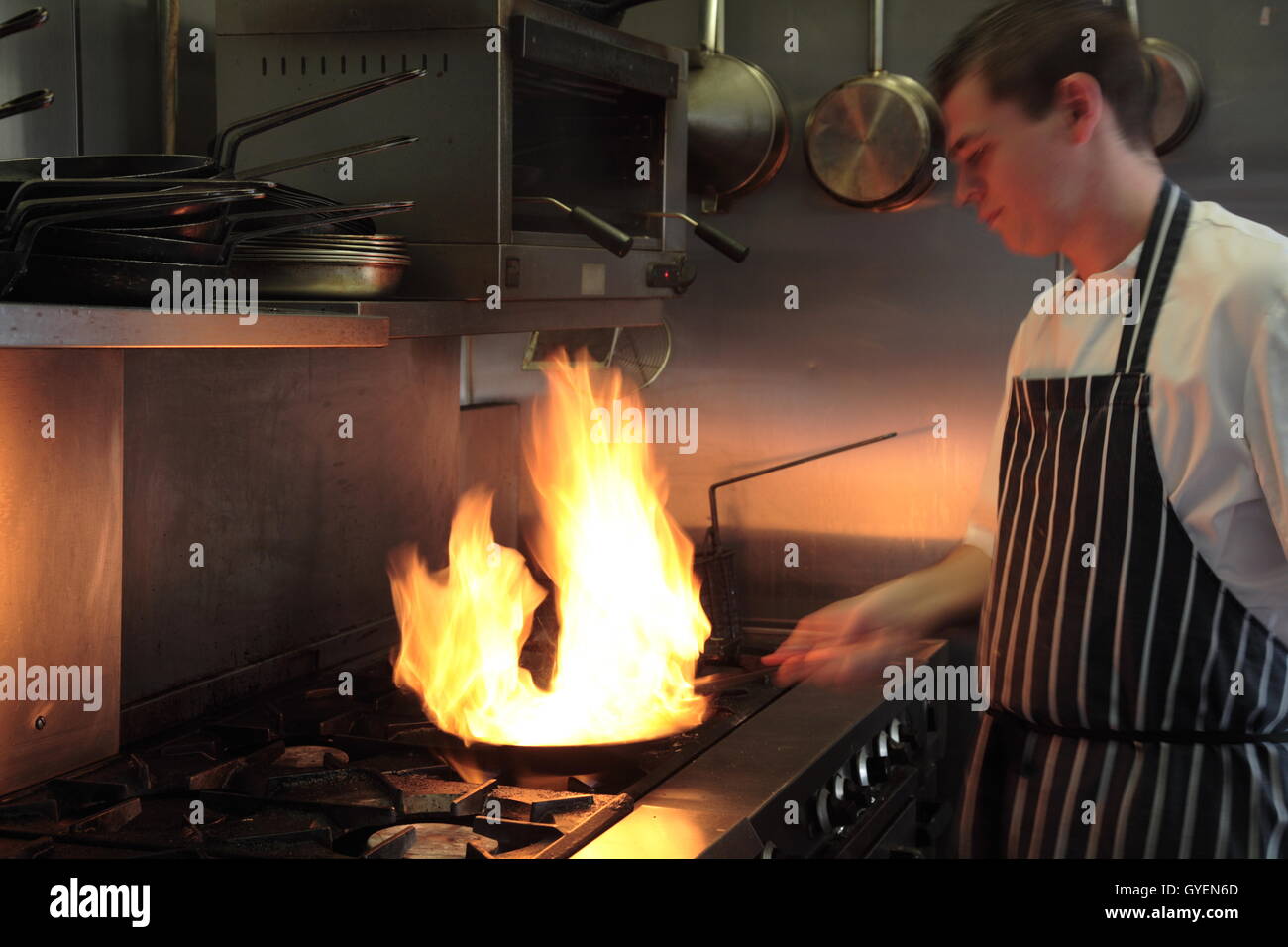 A chef flambes a dish in his kitchen Stock Photo