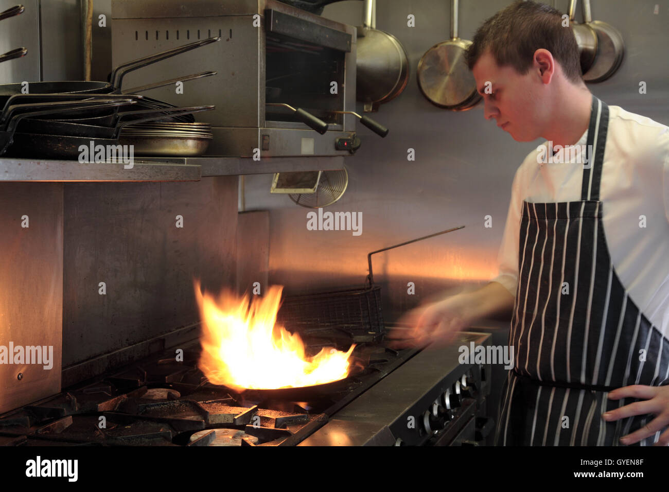 A chef flambes a dish in his kitchen Stock Photo