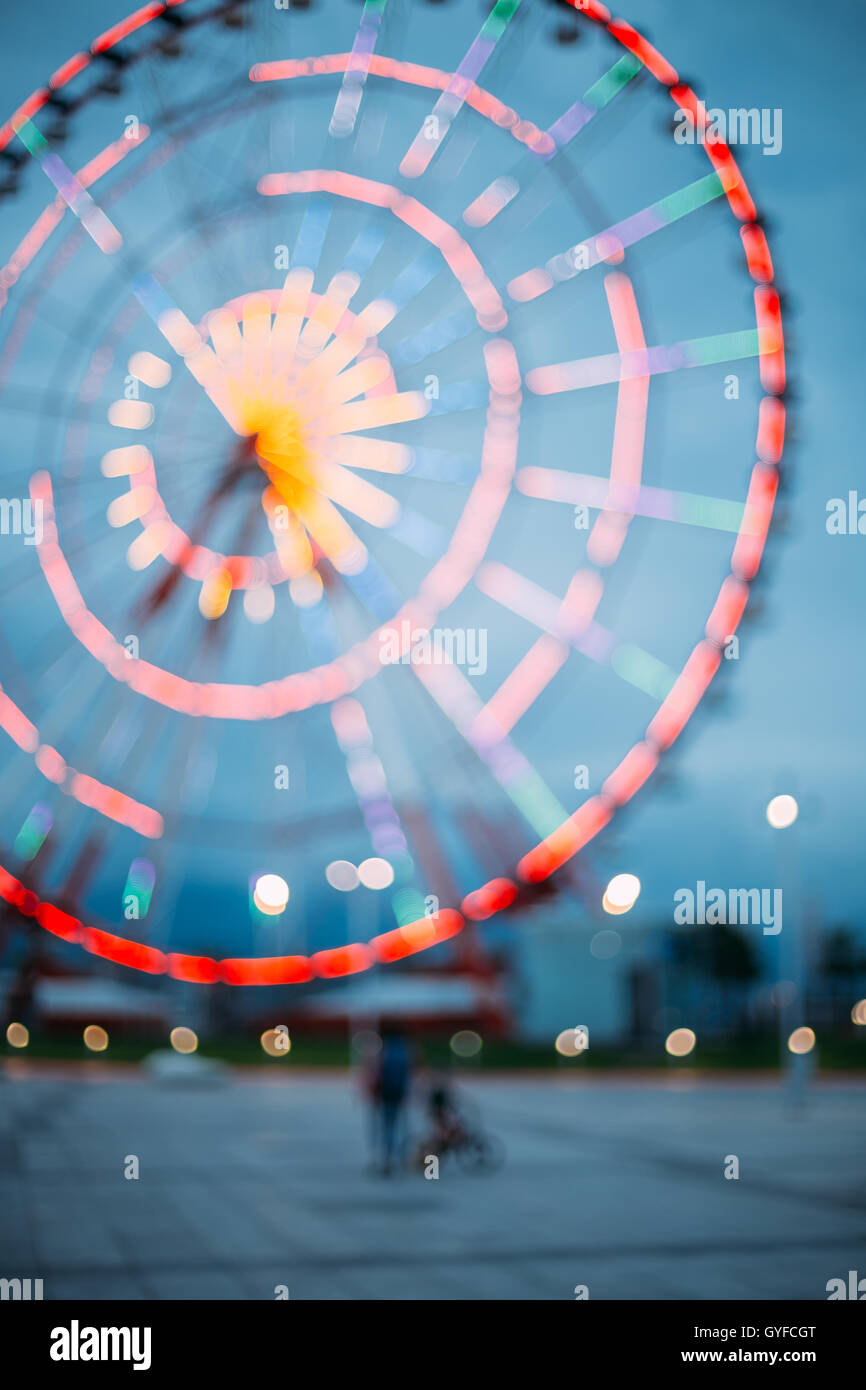 Abstract Motion Blur Image Of Brightly Colorful Illuminated Ferris Wheel In Amusement City Park On Black Blue Evening Sky Bokeh Stock Photo