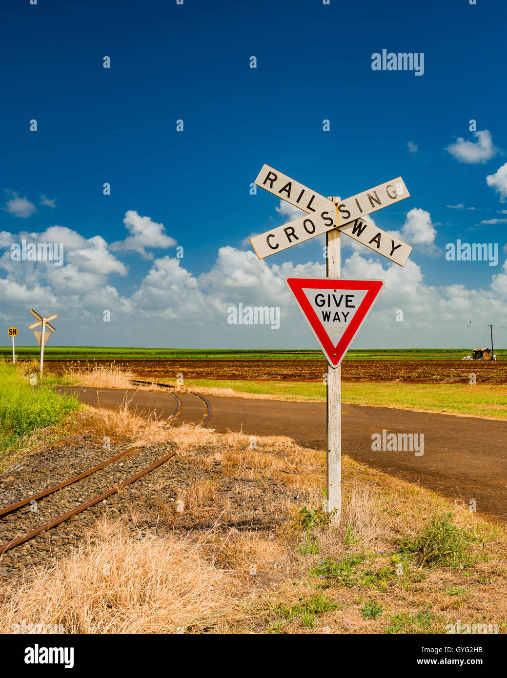 Railway crossing at sugar cane farms near Bundaberg, Queensland, Australia Stock Photo