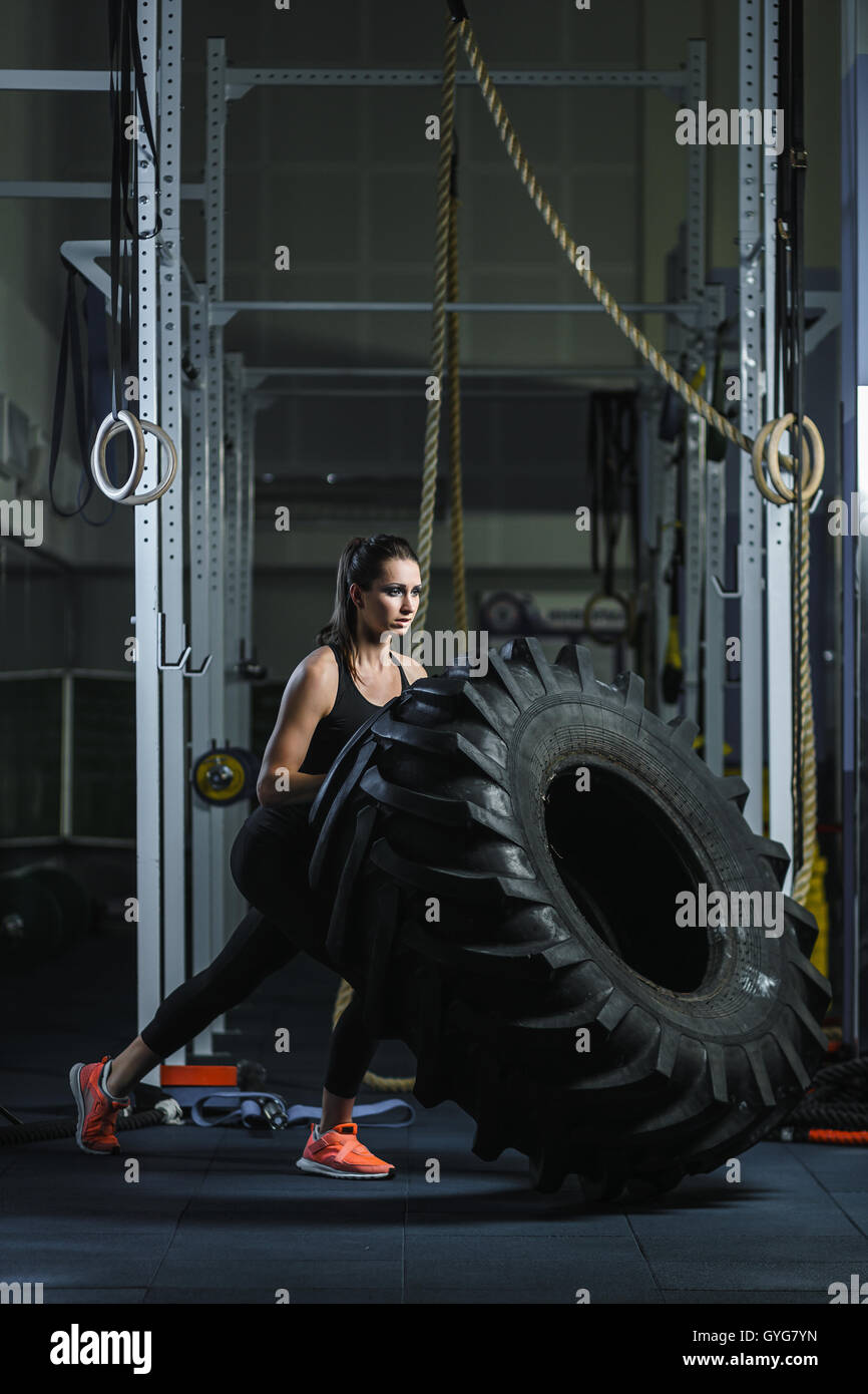 Concept: power, strength, healthy lifestyle, sport. Powerful attractive muscular woman CrossFit trainer doing giant tire workout Stock Photo