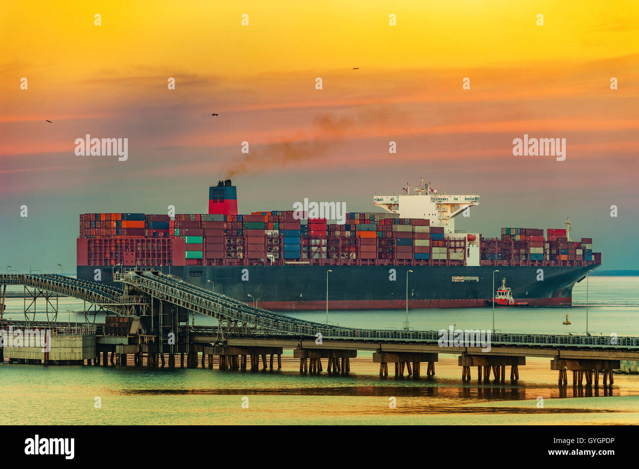 Tugboat assisting container ship on sea in the morning. Stock Photo
