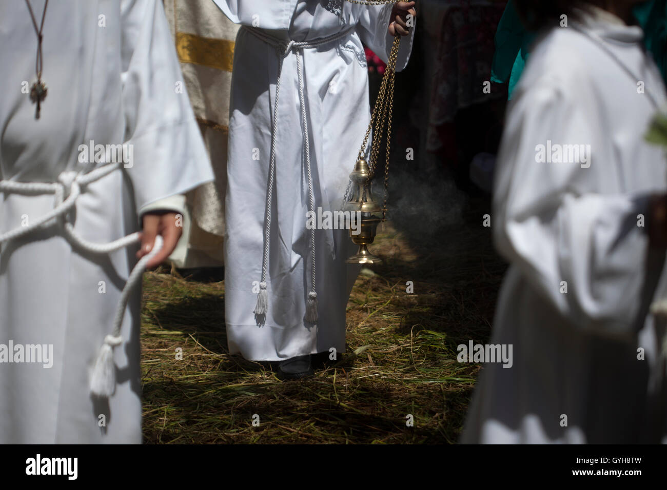 Altar boys spread incense in a street covered with sedge during Corpus Christi religious celebration in El Gastor, Spain Stock Photo