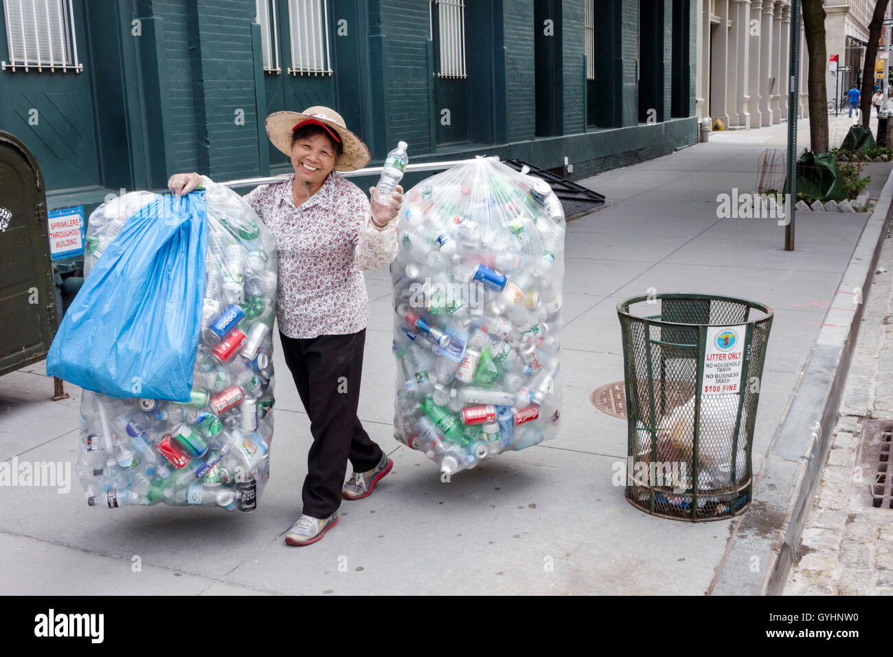 New York City,NY NYC Lower Manhattan,Tribeca,Asian adult,adults,man men male,woman female women,mature,recycling,aluminum cans,plastic bags,carrying p Stock Photo