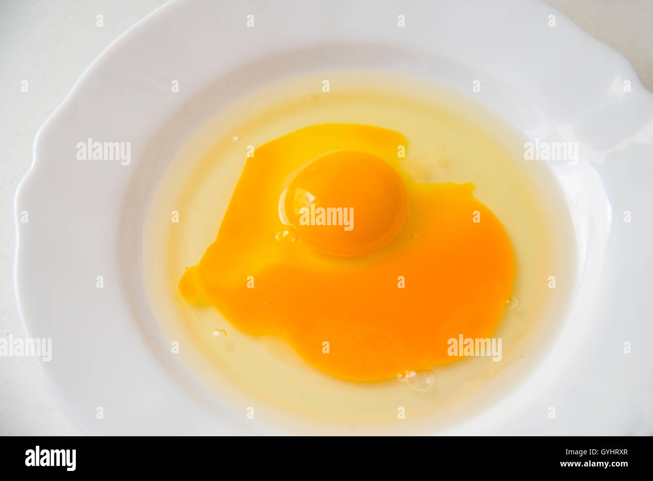 Two eggs in a dish, one of them with broken yolk. Stock Photo