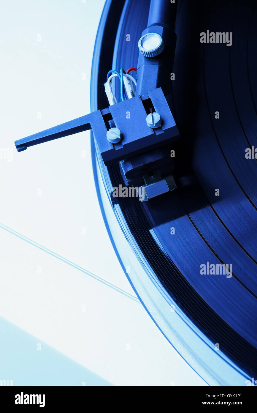 Turntable playing vinyl record with music. Useful equipment for DJ, nightclub and retro hipster theme or audio enthusiast. Blue hipster tone. Stock Photo