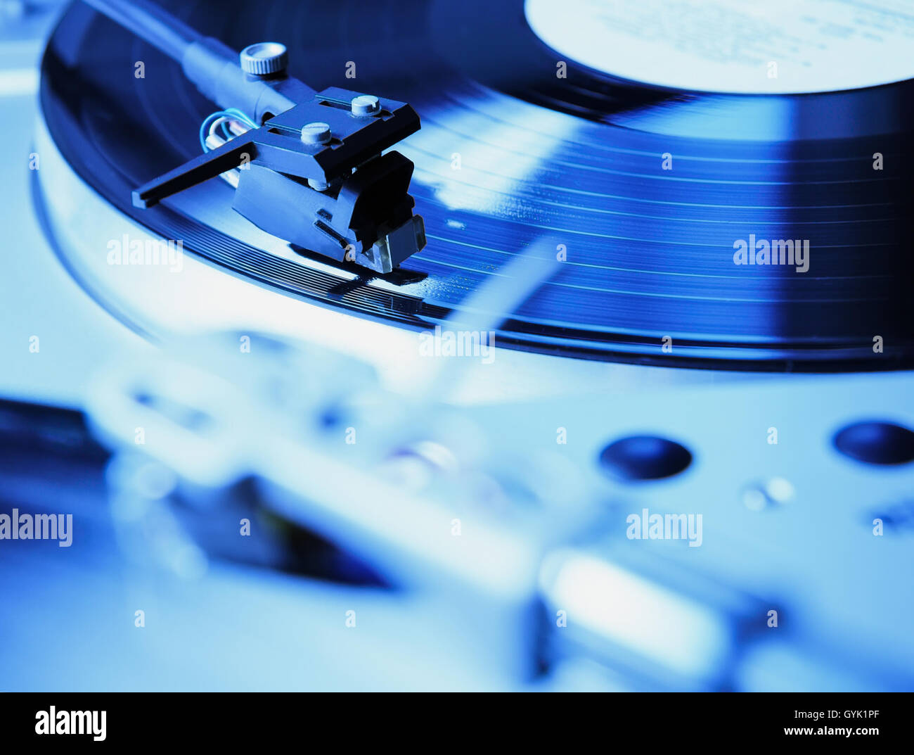Turntable playing vinyl record with music. Useful equipment for DJ, nightclub and retro hipster theme or audio enthusiast. Vibrant blue color Stock Photo