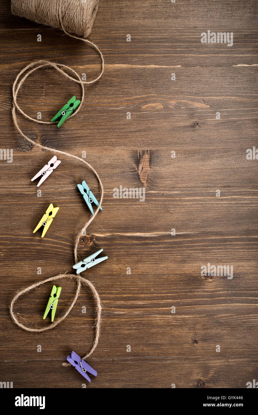 Small colored pins and rope on wooden background Stock Photo