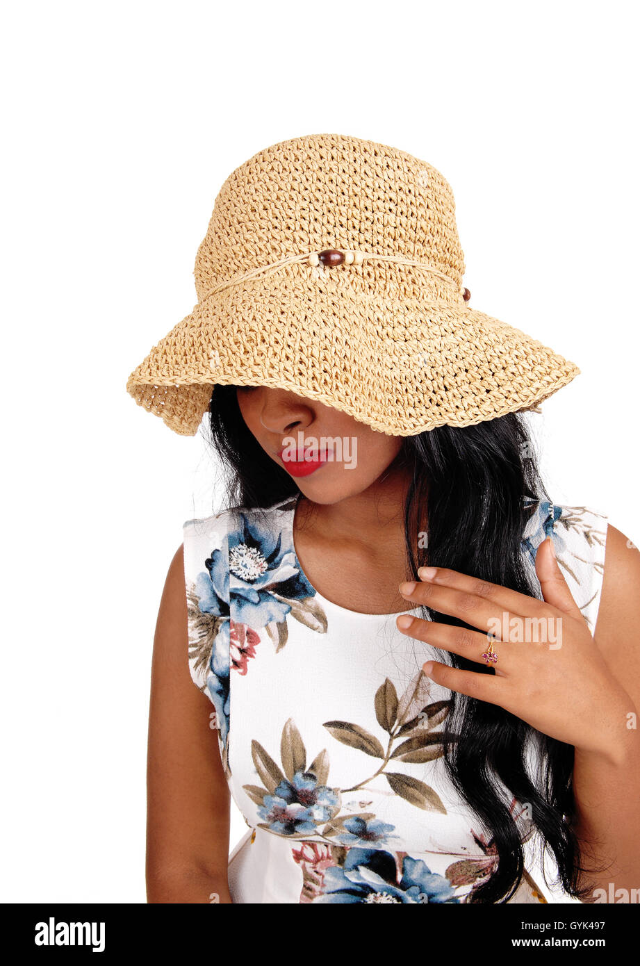 A mystery woman with a beige straw hat and long black hair looking  down with one hand on chest, isolated for white background. Stock Photo