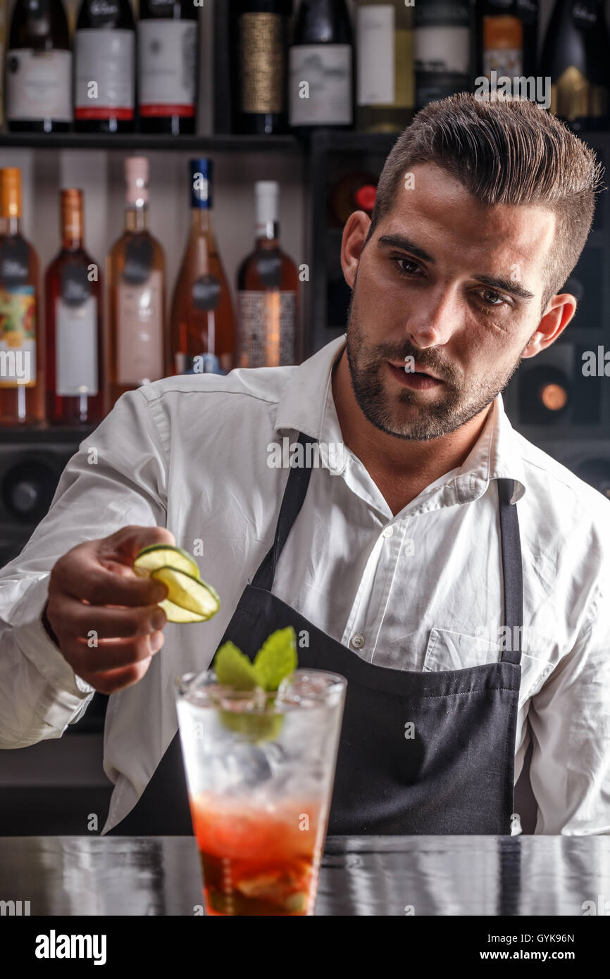 Barman decorating cocktail with lime Stock Photo