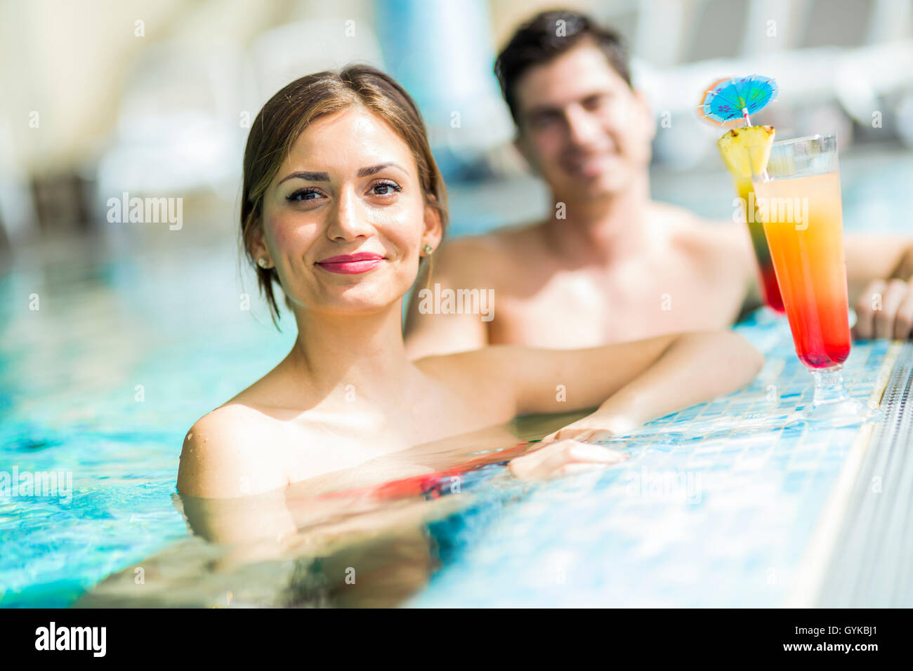 Young people drinking cocktails by the swimming pool and relaxing Stock