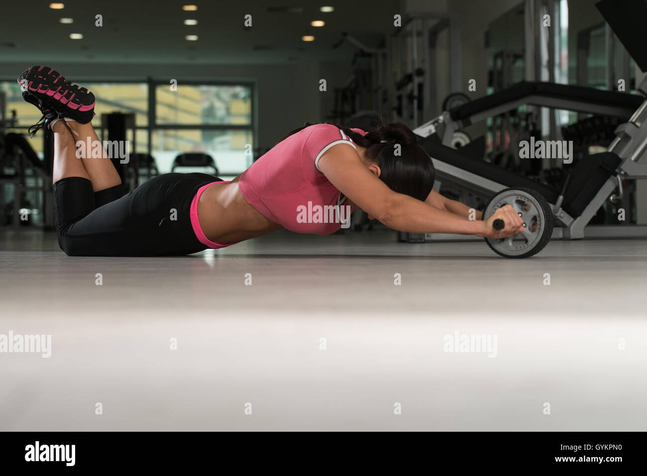 Attractive Woman Exercising With Wheel Roller For Abs On Floor In Gym ...