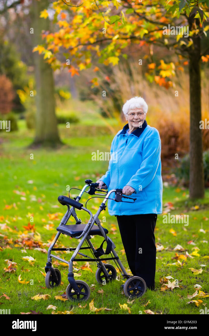 Happy senior handicapped lady with a walking disability enjoying a walk ...