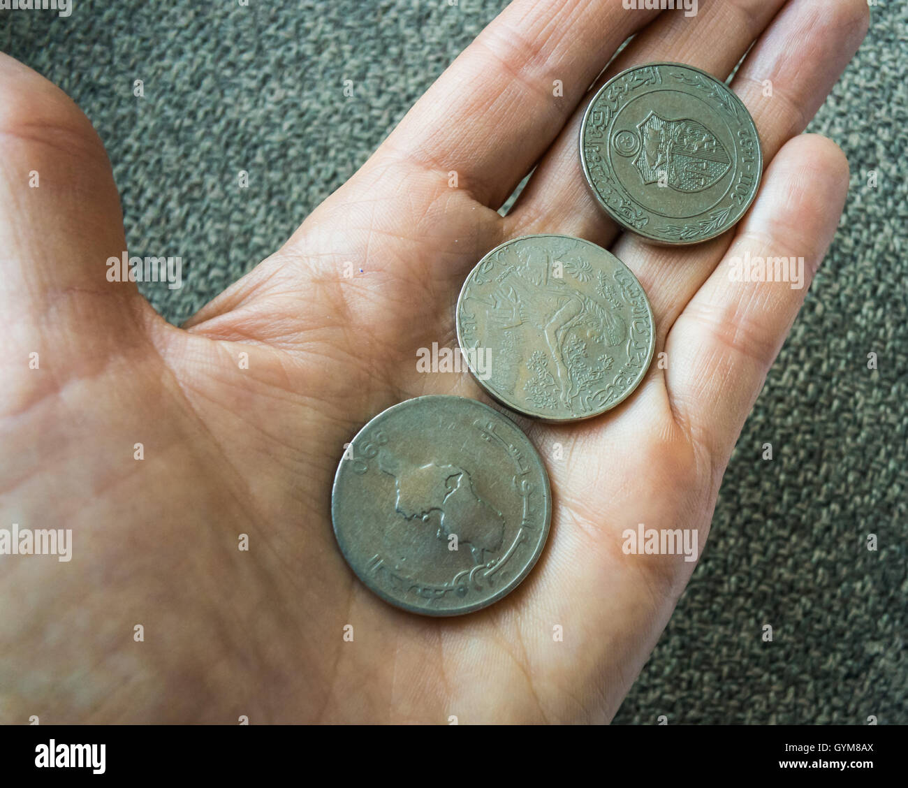 Three Tunisian coins on the woman's palm Stock Photo