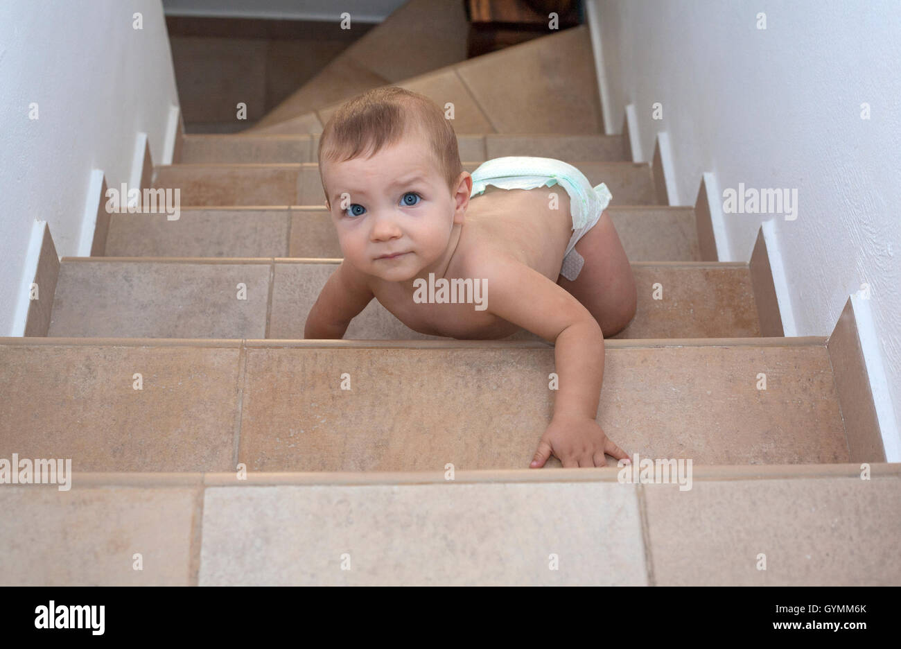 Baby boy crawling up the stairs. High angle view Stock Photo