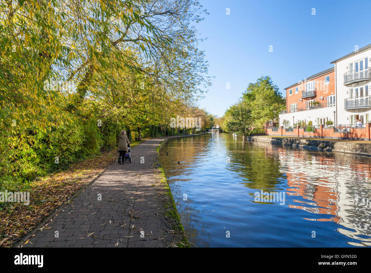 Woman walking with a pushchair along the towpath of the Nottingham and Beeston canal during Autumn, Nottingham, England, UK Stock Photo
