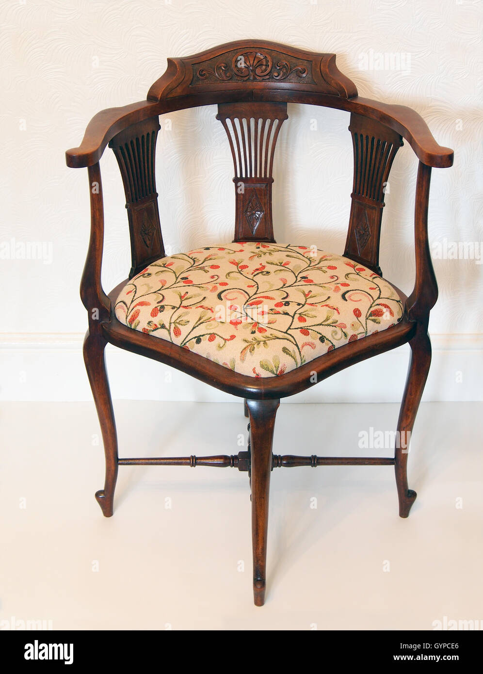 Edwardian corner chair with turned stretchers, a tapestry seat and carved splats and back. Stock Photo