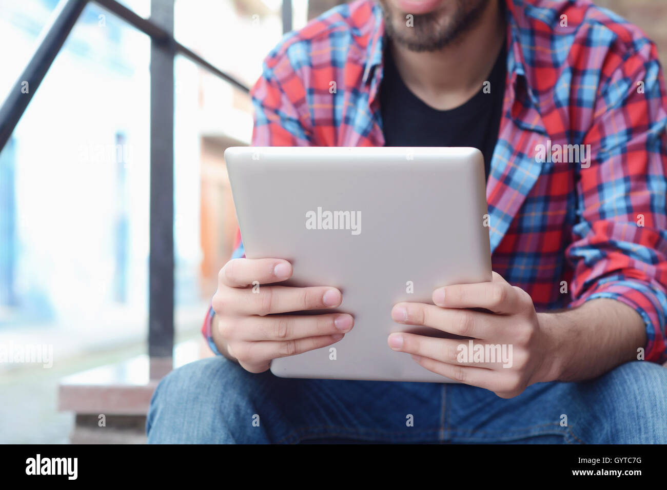 Young latin man touching at tablet at the street. Stock Photo
