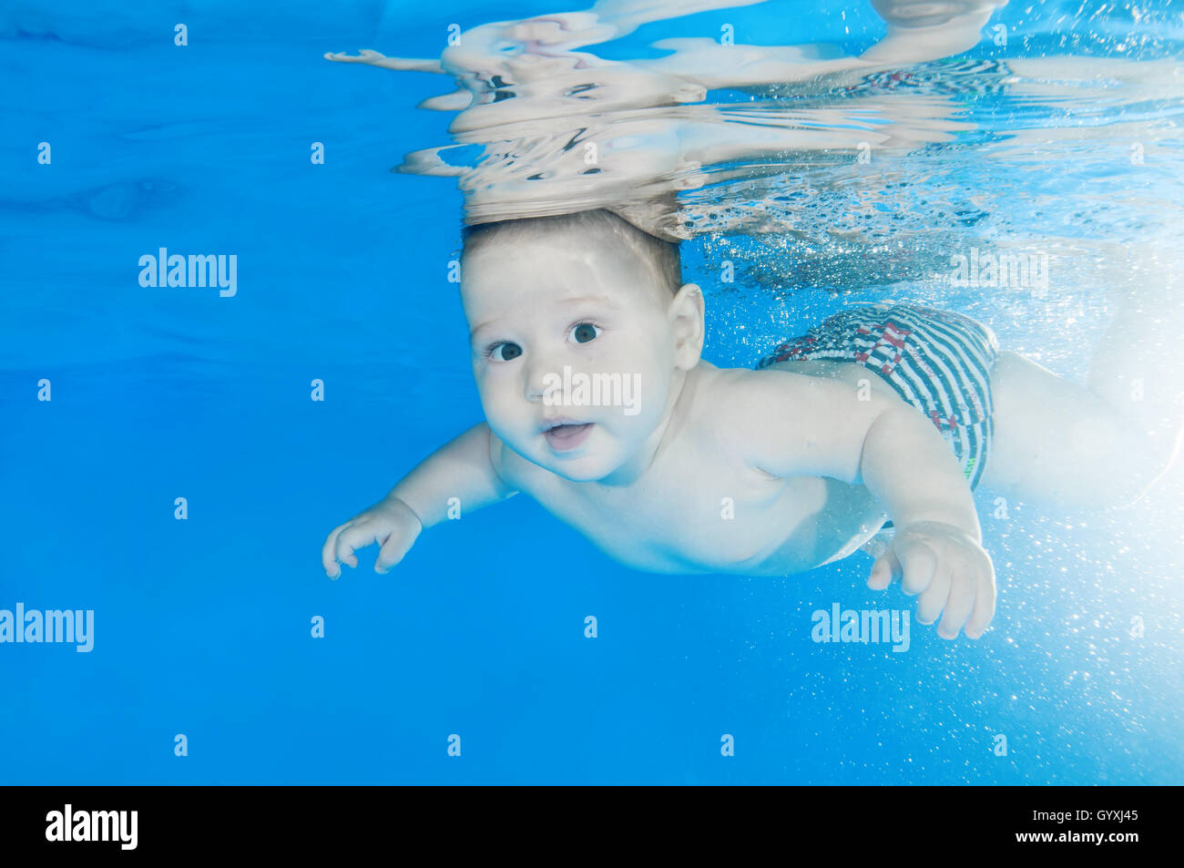 6 months infant boy learning to swim underwater in waterbaby class in