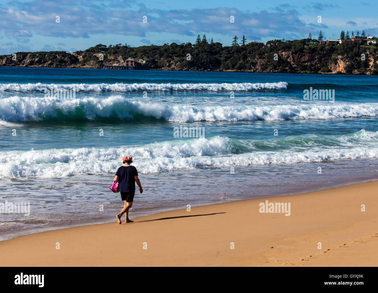 Senior woman walking on deserted beach Stock Photo