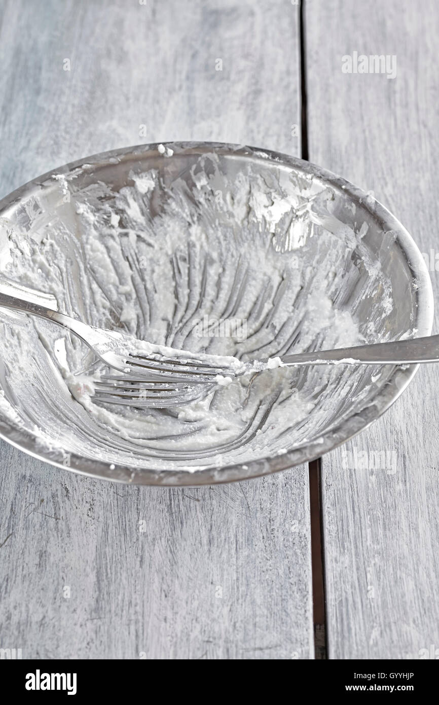 Dirty silver bowl after cottage cheese breakfast with forks on rustic wooden table. Stock Photo